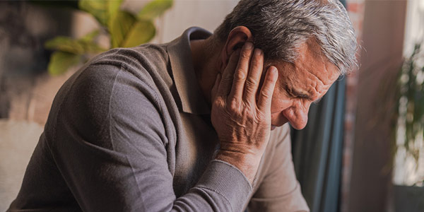 A man sitting with hand against hi face thinking deeply.