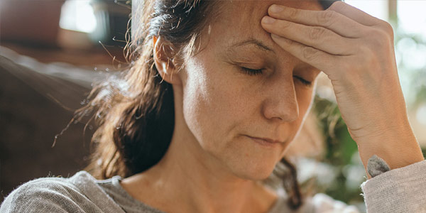 A woman with her hand on forehead thinking deeply.