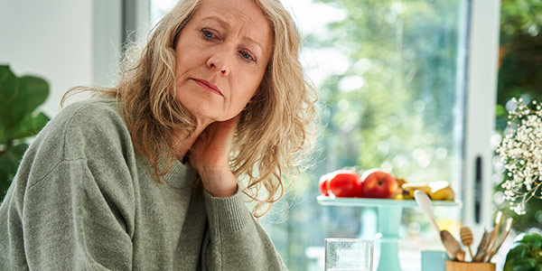 A woman sitting in her home looking out with concern.